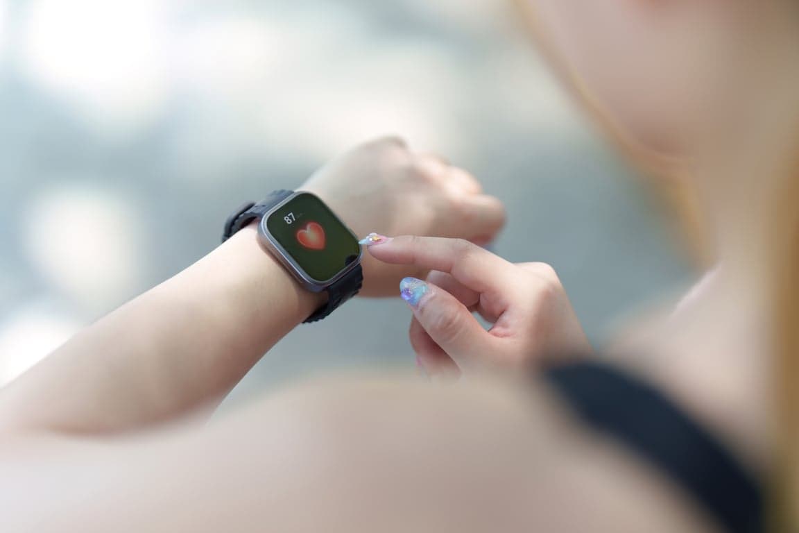 woman monitoring heart rate on smartwatch outdoors