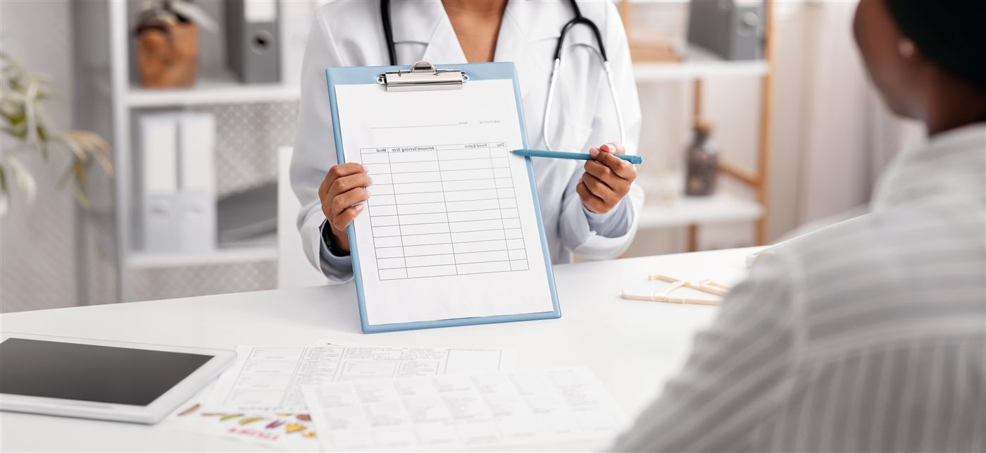 A doctor reviews a patient's health progress chart during a follow-up consultation